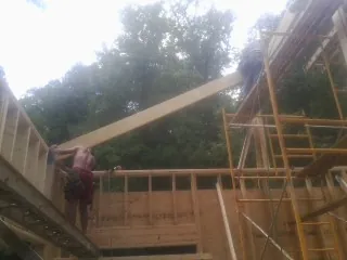 Carpenter raising a rafter beam on a new second story frame in Forest Lake