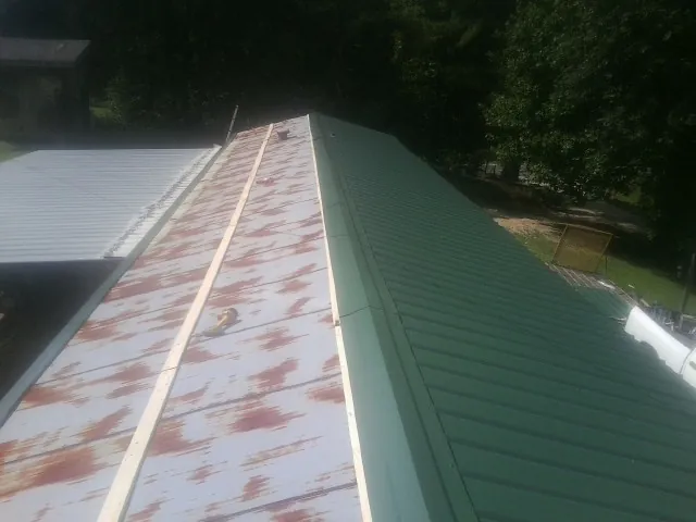 Old rusted panels beside newly installed green metal roofing — Wind Damage Roof Repair by Roofing Brothers in Forest Lake