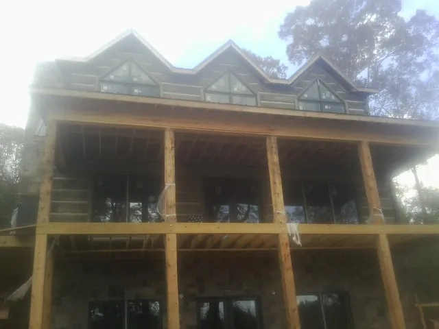 Dormers and porch framing on a large log home under construction — Roof Coating work by our crew in Forest Lake