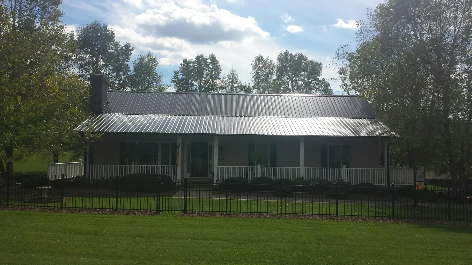 Gray metal roof on a brick ranch with a full width front porch — Gutter Guard Installation work by our crew in Forest Lake