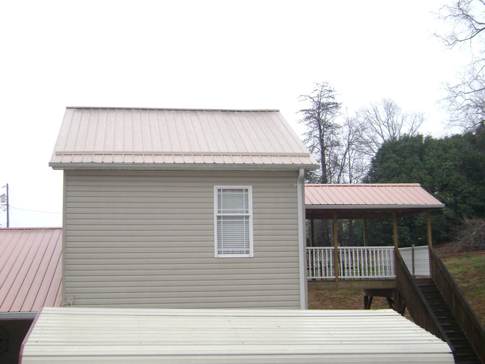 Tan metal roofs on a two story addition and attached porch, from a Roof Replacement job in Forest Lake