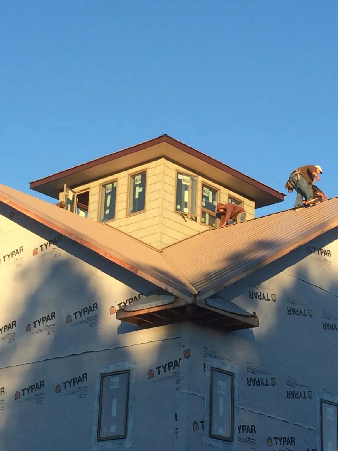Roofers working around a rooftop cupola on a new metal roof at sunset — Roof Waterproofing in Forest Lake by Roofing Brothers